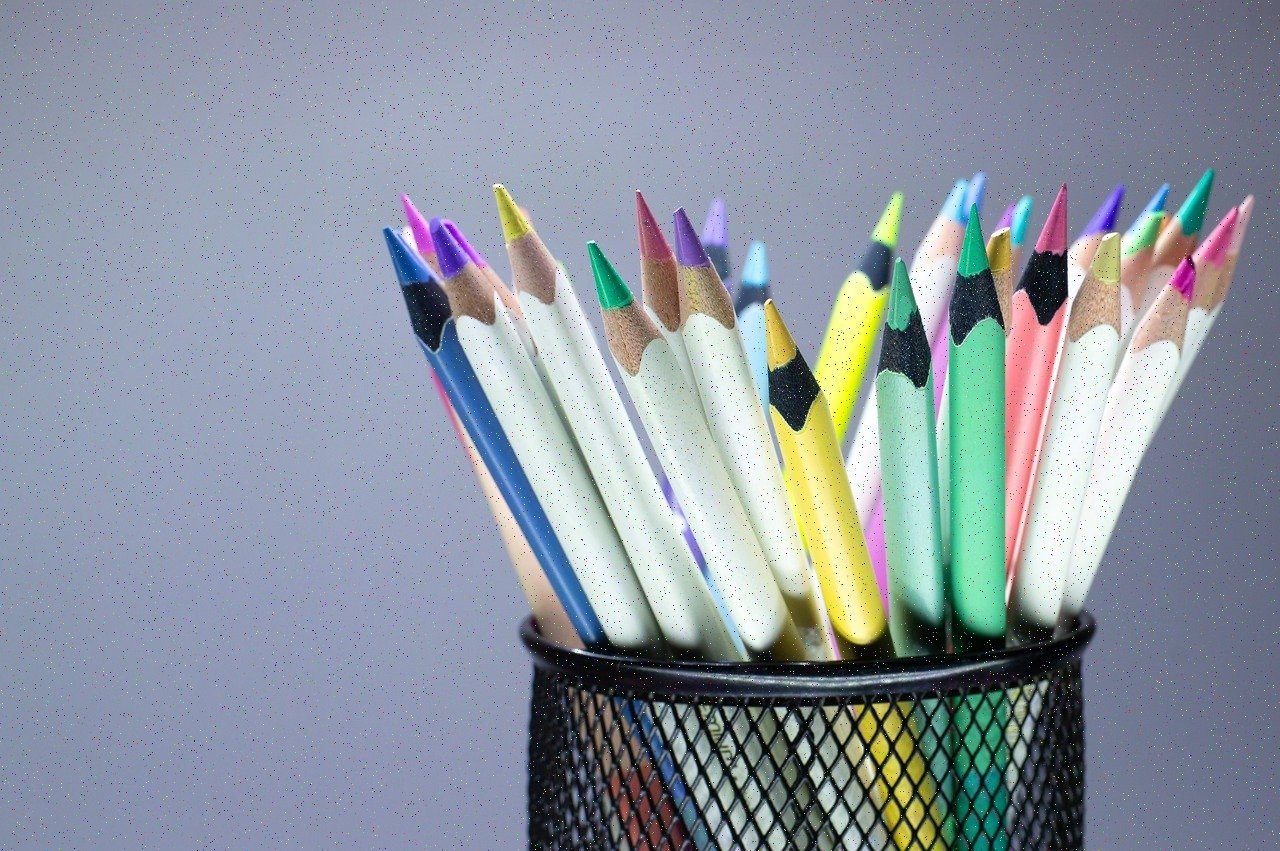 Colorful pencils standing in a mesh cup on a desk