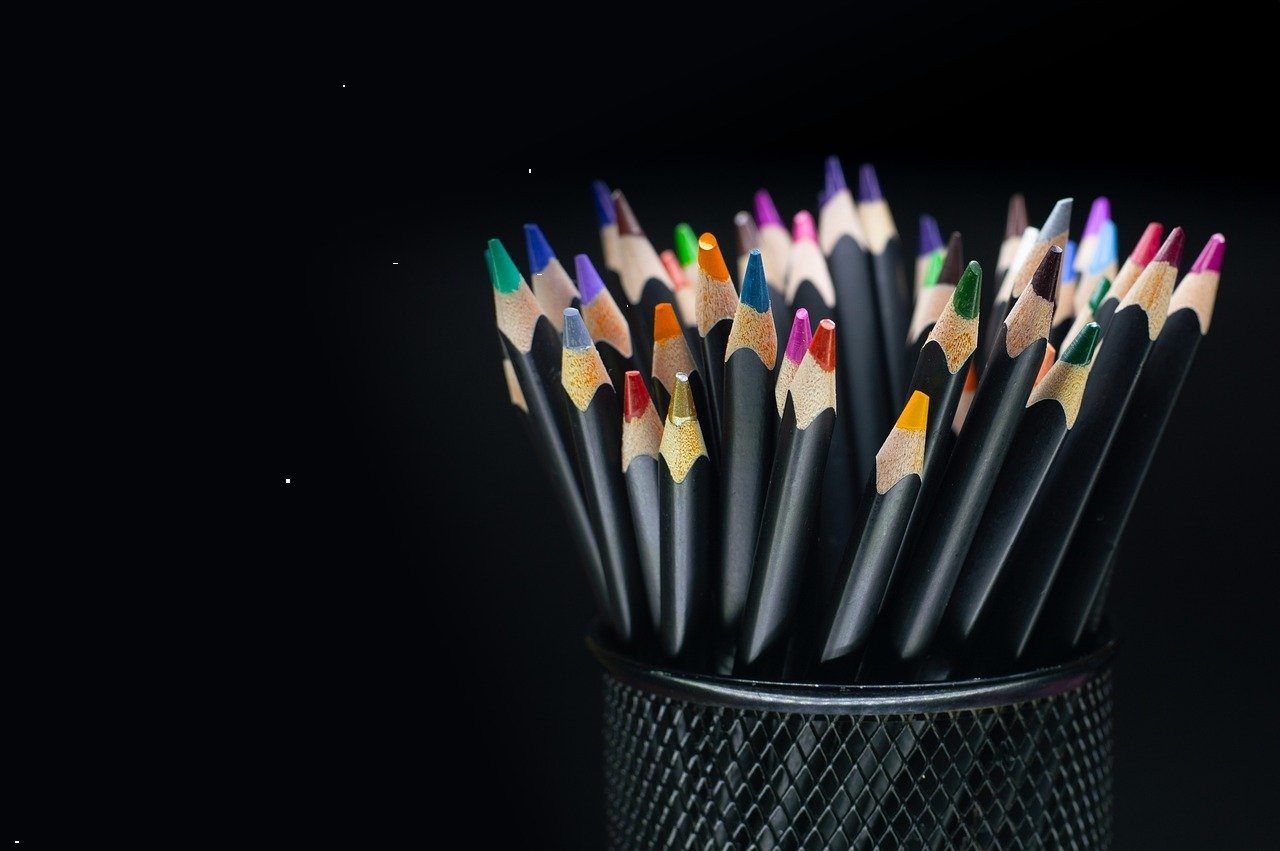 Rows of colored pencils on a dark background, used for character design color studies